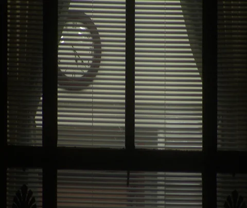 View through illuminated office window of analog clock at 5:20. Stock Footage 86749900
