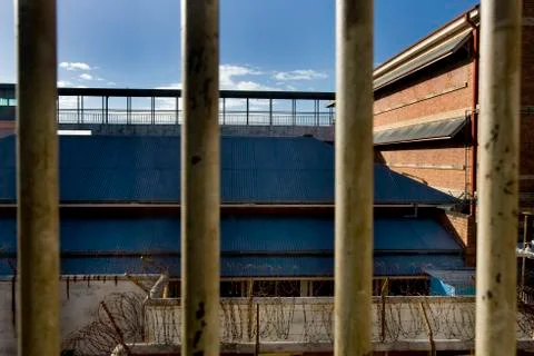 View through iron bars on prison walls during a sunny day Stock Photos