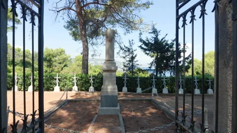 View through an iron gate of a cemetery with white cross headstones and pine Stock Footage 344809957