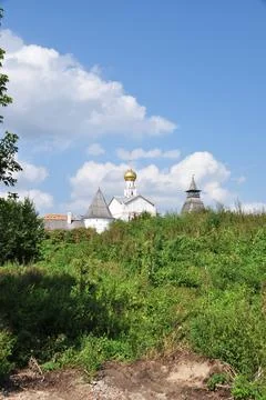 View through large trees to the buildings of the monastery. Stock Photos