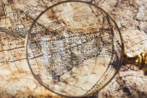 View through magnifier on old map, showing "America" word. Stock Photos