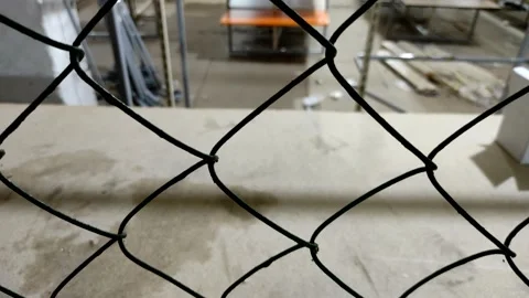 A view through a metal grid of an empty warehouse, room, or production building. Stock Footage 201290769