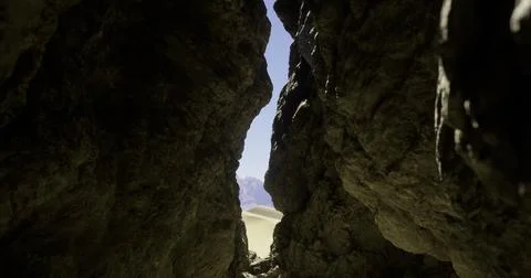 View through a narrow rock formation revealing a desert landscape at noon Illustrazione stock