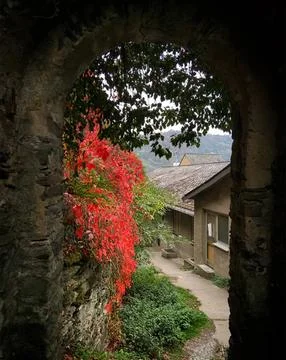 View through an old stone archway to a garden with fall trees Stock Photos