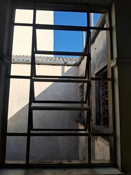 View through an old window with metal bars. Urban scene with natural daylight Stock Photos