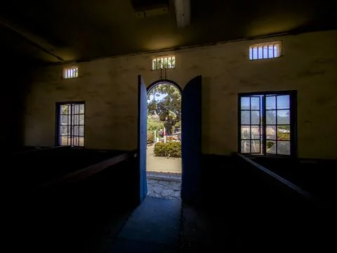 View through an open doorway from a dark stable to a sunny garden Fotos de archivo