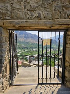 View through open gate from stone structure, overlooking valley and mountains Stock Photos