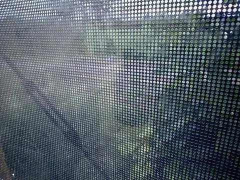 View Through Perforated Window with Blurred Green Landscape Stock Photos