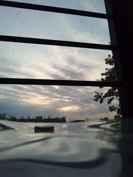 View through pergola structure showing cloudy sky and distant cityscape horizon Stock Photos