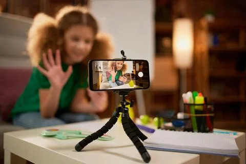 View through phone screen. Cute little elementary schoolgirl recording video Stock Photos