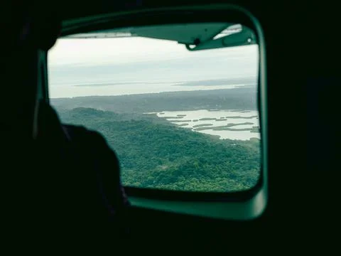 View through plane window shows green hills and rivers far below Stock Photos
