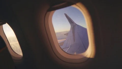 View through the portholes of the plane to the setting sun clouds and the sky Vídeos de archivo 84585853