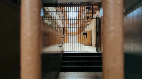 View through prison bars inside an old abandoned jail corridor with locked gates Stock Footage 335750838