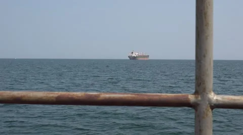 View through railing ship on the horizon with cargo ship Stock Footage