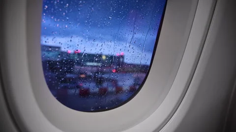 View through a rain-covered airplane window of a wet airport apron with blurred Stock Footage 342282898