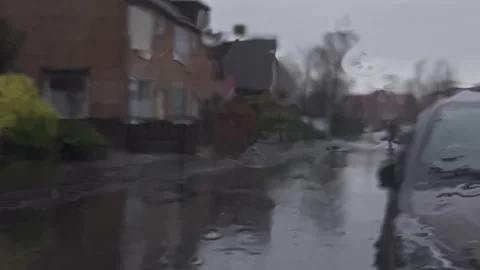 View through a rain covered car window looking out at a gloomy suburban street Stock Footage 344159163