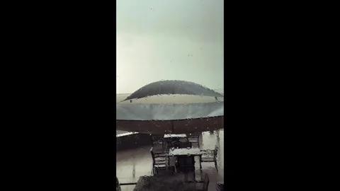 View through a rainy window of a cafe or restaurant terrace with an umbrella or Stock Footage 313594855