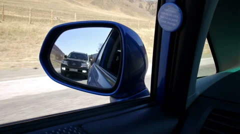 View through rear car mirror reflection to overtaking automobile Stock Footage 49968384