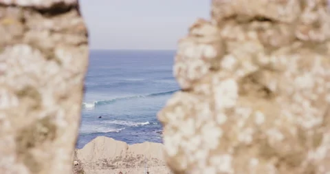 View through rocks on cliff with wavy ocean splashing and moving in slow motion Stock Footage 156281456