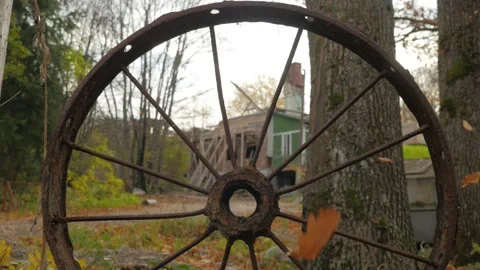 View through rusty vintage wheel of abandoned old wooden house in countryside Stock Footage 162825066