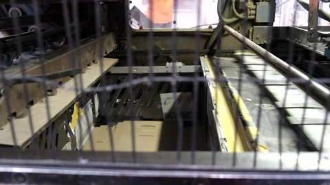 View through a safety cage grid of automated machinery operating in a manuf.. Video stock 337670661