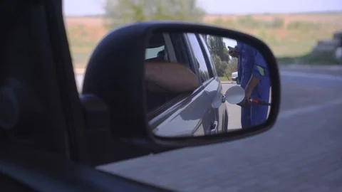 View through the side mirror of how to fill a car Stock Footage 114829260