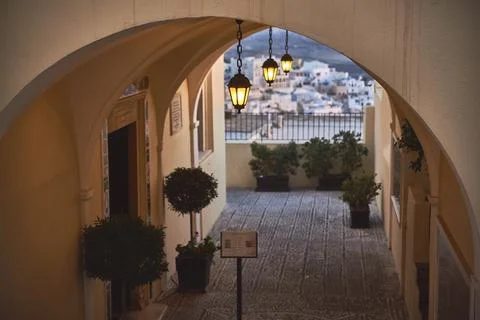 View through a stone archway with hanging lanterns overlooking a village cour Stock Photos