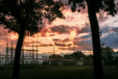 View through the trees to a substation with a red sky Stock Photos