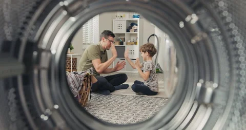 A view through the washing machine drum into the bathroom. A son and father are Stockbeeldmateriaal 200851398