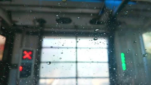 View through water beaded windshield inside automated car wash Stock Footage 339250418