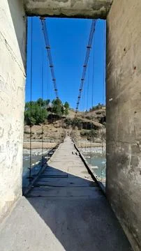 View through weathered concrete pillars frames an old wooden suspension brid Stock Photos