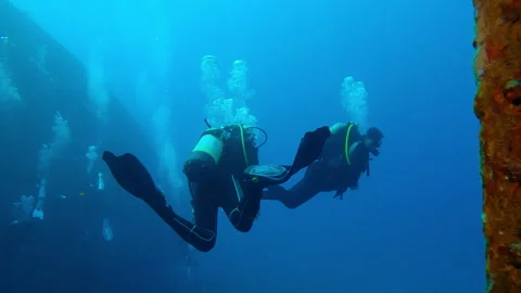 View through wheelhouse window of group scuba divers swimming on wreckship Stock Footage 295919787