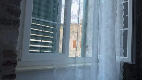 View through a white lace curtain and open window looking at old stone Stock Footage 341663214
