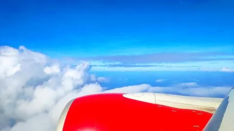 View through the window of an airplane during a flight over clouds during the Stock Photos