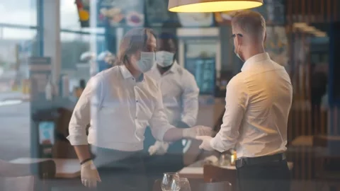 View through window of cafe owner measuring temperature of waiters with infrared Video stock 141431697