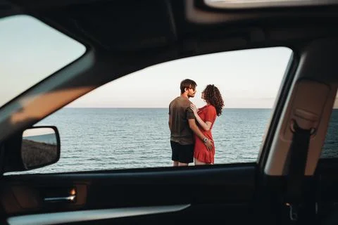 View Through Window of the Car Young Couple Standing on the Background of Sea 스톡 사진