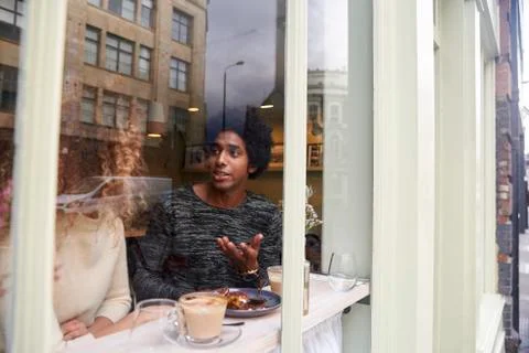 View Through Window Of Couple Enjoying Drink In Coffee Shop Stock Photos