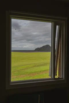 View Through a Window of Green Field, Rocky Hill, and Coastline Stock Photos