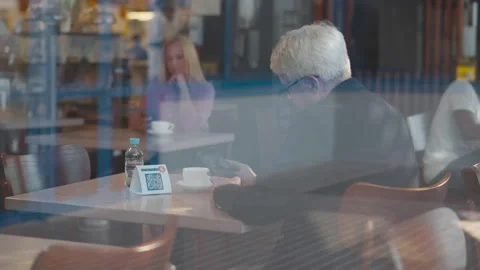 View through window if mature businessman scan qr-code with cellphone in Stock Footage 171263600