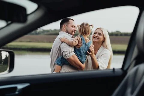 View Through Window Inside of Car, Happy Young Family with Kid Hugging Together Stock Photos