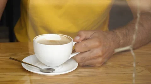 View through the window of a man's hand placing a white coffee mug on a saucer Stock Footage 220698142