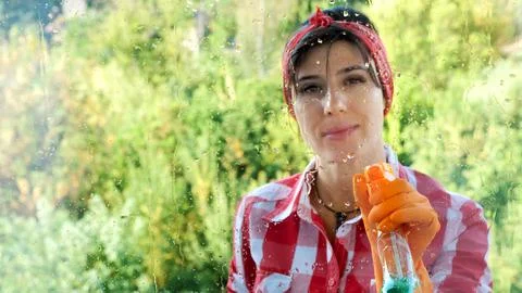 View through the window, smiling Beautiful woman in gloves, Cleaning Window by Stock Photos