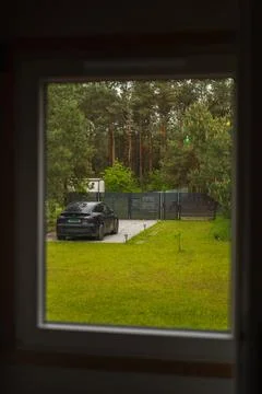 View Through a Window of a Tesla Car by a Gravel Driveway and Forest Stock Photos