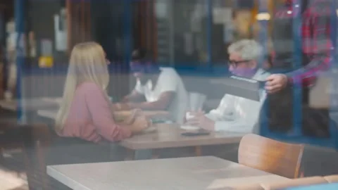 View through window of waiter setting RESERVED sign on restaurant table Stock Footage 135226030