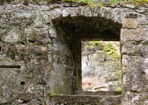 View through a window in the wall of the ruins of an old water mill Stock Photos