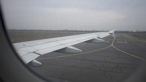 View through window on wing of airplane taxiing down runway, preparing for Stock Footage 243305132