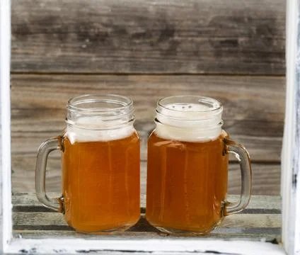 View through windows of two glass jars filled with frosty cold beer on top of Stock Photos