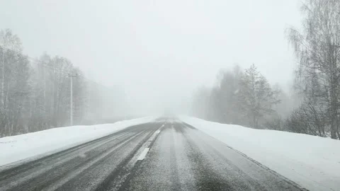 View through the windshield of a car on an empty snowy and icy road in winter in Stock Footage 160204620