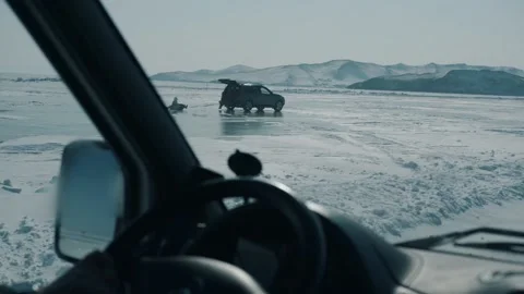 A view through the windshield of a car at people riding tubing tied to a Vídeo Stock 153270231