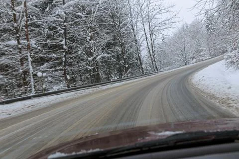 View through the windshield of the car on the road and snow-covered trees, sn Stock Photos